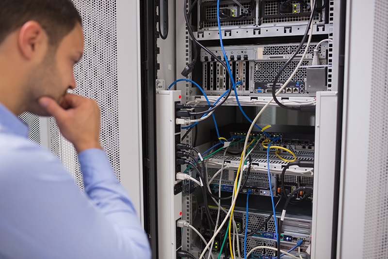 Ingeniero frente a un rack de servidores, con cables y equipos visibles.